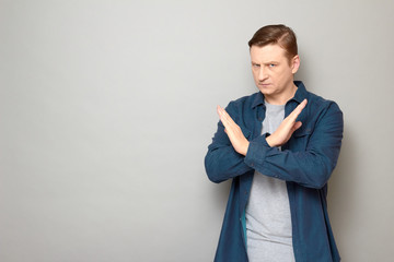 Portrait of serious man making cross with hands, showing stop gesture