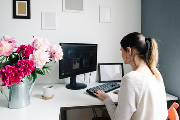 peonies in a garden watering can, a desktop in the home. woman at work