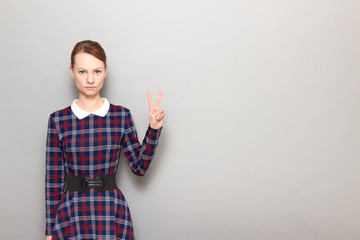 Portrait of serious girl showing victory sign or number two