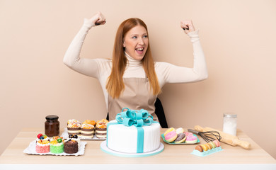 Obraz na płótnie Canvas Young redhead woman with a big cake celebrating a victory