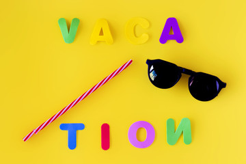 Colorful letters forming the word vacation with a straw and sunglasses on a yellow background