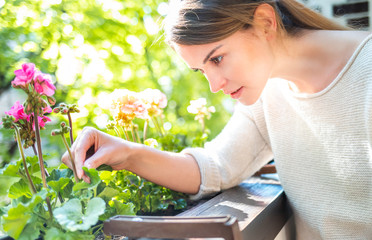 Woman looking at flowers on balcony checking for pests and diseases