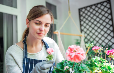 Woman looking at flowers on balcony checking for pests and diseases