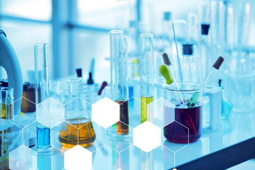 Close up open glass conical flasks standing in line with colorful liquids inside, chemical...