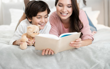 Female parent and her son perusing a book