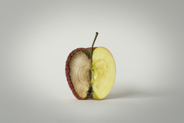 red apple with one half good and the other half rotten, concept of time, fruit that becomes garbage and that is thrown away, white background, isolated object - 352630858