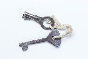 Two old keys tied with a white rope. Keys lie on a white background. The keys are rusted. photo above