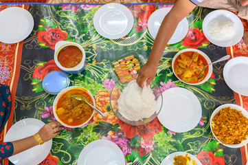 Flat lay Indian food. a hand taking Idiyappam or string hoppers is a popular traditional breakfast cuisine of Kerala with chicken curry during celebrate a Eid Mubarak in morning at home. 