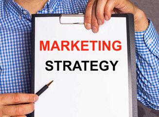 Marketing strategy - an inscription on a white sheet of paper held by a businessman