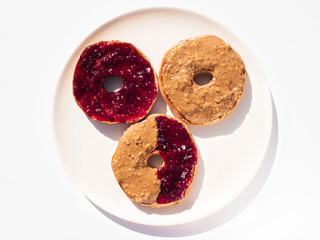 A trio of cinnamon and raisin bagels smothered in crunchy peanut butter and raspberry jam