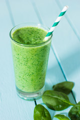 Fresh spinach smoothie on blue table. Healthy eating concept.