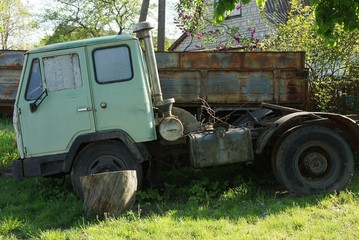 Fototapeta premium one old big lorry with a green cab is standing in the grass outdoors on the street