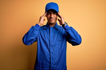 Young african american mechanic man wearing blue uniform and cap over yellow background with hand...