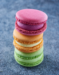 Fototapeta na wymiar Stack of three colorful macaroons on the table. Perfectly shaped macaroons, sweet dessert