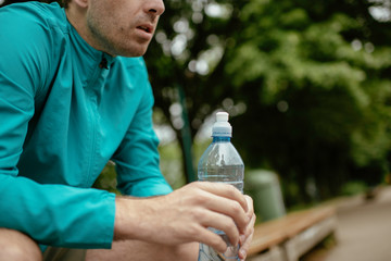 Fit young man taking rest from running. Two friends training outdoors.