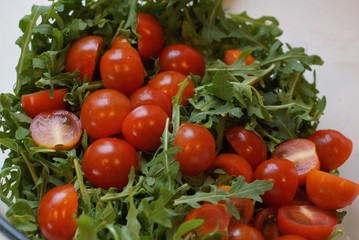 food from green salad and chopped fresh red tomatoes on a white background