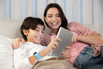 Boy with a gadget sitting next to his mother