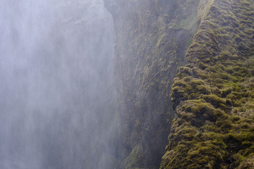 spray and mist from Skogafoss Icelandic waterfall helps the moss and lichen grow on the cliffs surrounding the falls