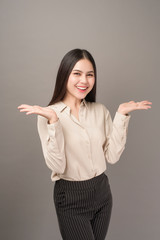 Portrait of Beautiful business woman is showing something on gray background