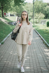 Fototapeta premium beautiful young girl student with a backpack walks on a footpath