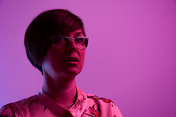 High Fashion model woman in colorful bright lights posing in studio.