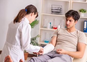 Obraz premium Young man with bandaged arm visiting female doctor traumatologis