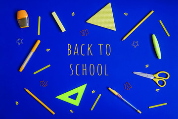 Stationery on blue. Bright stylish flat lay. Different yellow tools with text Back to school in centre.