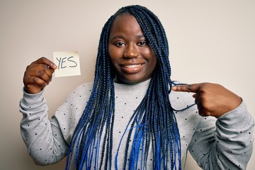 Young african american plus size woman with braids holding reminder paper with yes message with...