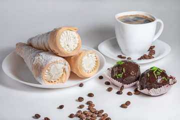 Puff rolls with cream on a white plate and black coffee