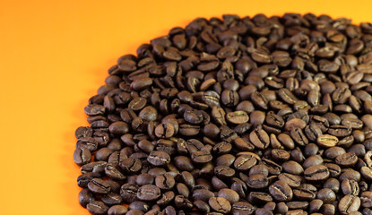 Coffee beans on a bright background. Coffee granules on an orange table. Texture of coffee beans.