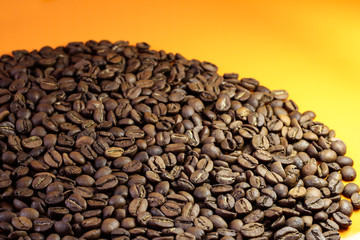 Coffee beans on a bright background. Coffee granules on an orange table. Texture of coffee beans.
