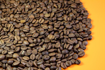 Coffee beans on a bright background. Coffee granules on the yellow table. Texture of coffee beans.