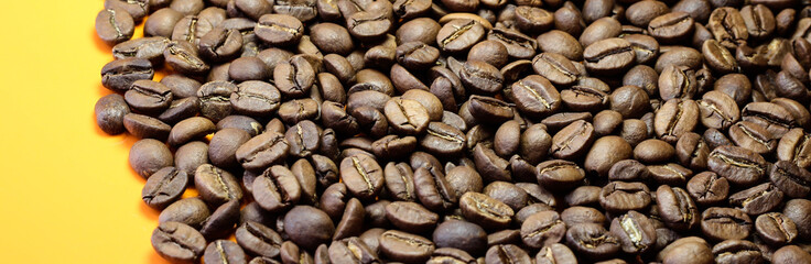 Coffee beans on a bright background. Coffee granules on the yellow table. Texture of coffee beans.