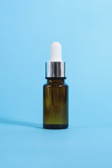 A cosmetic jar with glass dropper on the blue background.