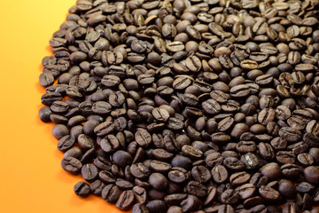 Coffee beans on a bright background. Coffee granules on the yellow table. Texture of coffee beans.