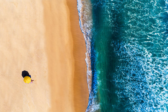 Aerial view of beach umbrella with a person sunbathing, at the Comporta Beach in Portugal. Concept for social distancing on the beach.