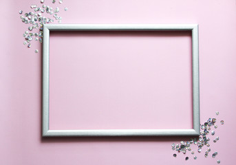 Silver frame with confetti and space for text on pink background.