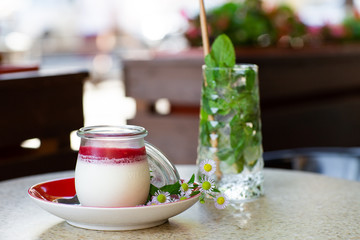 Vanilla Panna Cotta with Jelly of berries in glass jar. Italian dessert panna cotta. Classic Italian dessert creamy panna cotta with cherry sauce. Concept of pastry salon. Mojito and dessert.