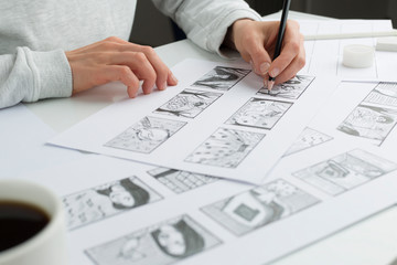 Hands of the artist draw a storyboard on paper. Storytelling. Story frames with heroes. - 352645462