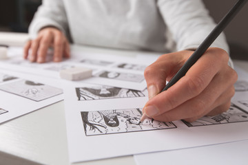 The animator artist draws in pencil a storyboard for the cartoon. Pre-production for the video film. The designer creates sketches for the comics. 
