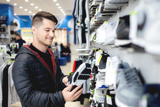 Young Man Looking For Sports Equipment At Sports Shop