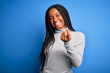 Young african american woman standing wearing casual turtleneck over blue isolated background Beckoning come here gesture with hand inviting welcoming happy and smiling