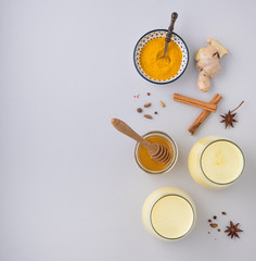 a glass of immune  Golden milk with turmeric, spices and honey on gray background