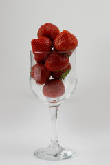 Fresh and ripe strawberries in a transparent glass round bowl isolated on white background