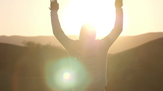 slow motion man performs sports exercises on the sun's background in his rays