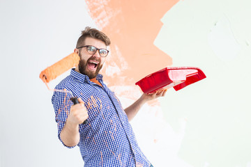 Funny man painting interior wall of home with paint roller. Redecoration, renovation, apartment...