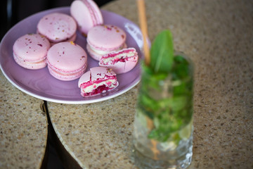 Macaroons on a plate on a gray background. French macarons isolated. Selective focus. Beautiful pink macaroons with coffee. Stylish arrangement sweet. Flat lay, top view. Macro photo.