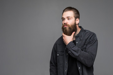 Fototapeta premium Handsome man hipster with long beard moustache and brunette hair in studio on grey background