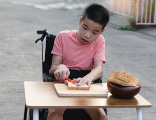 Disabled child on wheelchair is interested in skills development cooking food on home background,...