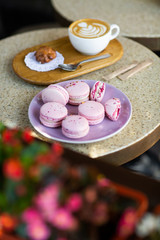 Macaroons on a plate on a gray background. French macarons isolated. Selective focus. Beautiful pink macaroons with coffee. Stylish arrangement sweet. Flat lay, top view. Macro photo.